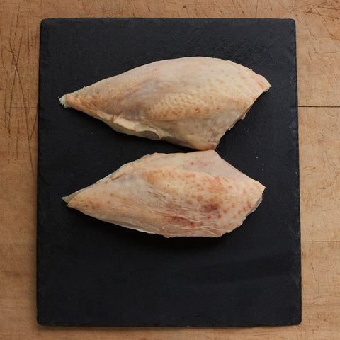 2 skin on free range chicken fillets on a board
