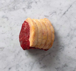 uncooked beef sirloin joint on a marble surface