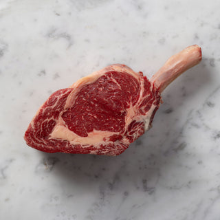 Raw tomahawk steak on a marble surface