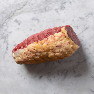 Uncooked beef topside roll on a marble surface