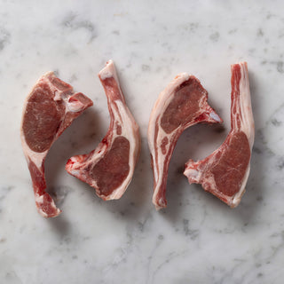 Four raw hogget chops on a marble surface