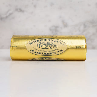 Roll of Netherend Butter in a gold packaging on white marble