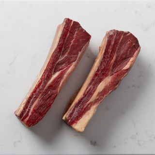two raw short ribs on a marble block