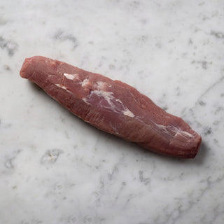 a whole pork tenderloin on a marble surface