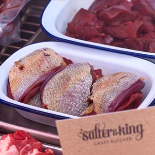 Wood pigeon breast fillets in a white enamel dish ready to cook